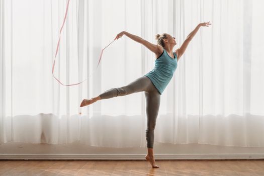 Flexible woman dancing with ribbon in swallow pose