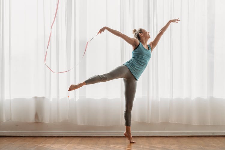 Flexible Woman Dancing With Ribbon In Swallow Pose