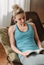 Focused woman resting on cushion while reading paperback book