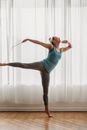 Graceful slim woman doing swallow pose in light room