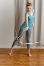 Full length of positive female gymnast standing on wooden floor and moving gymnastic ribbon from side to side