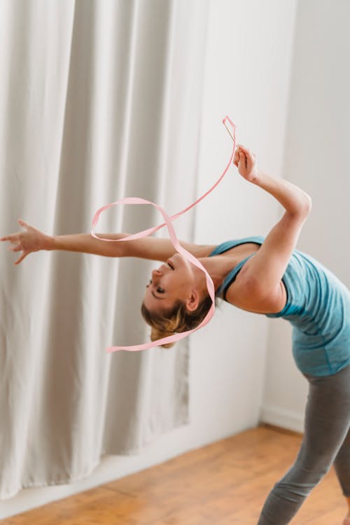 Young woman doing back bend exercise with gymnastic ribbon