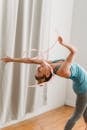 Young woman doing back bend exercise with gymnastic ribbon