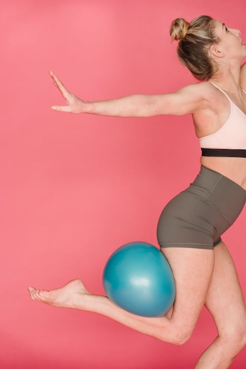 Slim woman training with fitness ball in studio