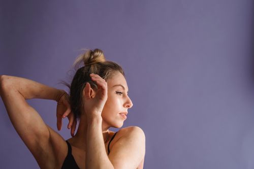 Free Calm female dancer with blond hair dancing and looking away against purple background in studio Stock Photo