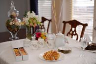 Elegant dining setup with croissants, tea set, and floral decor, perfect for brunch.
