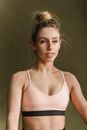 Slim young woman in black and pink top with opened mouth looking away against gray background in studio