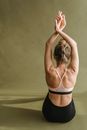 Unrecognizable graceful female dancer performing movement with raised arms in studio