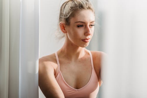 Peaceful young woman looking through window dreamily