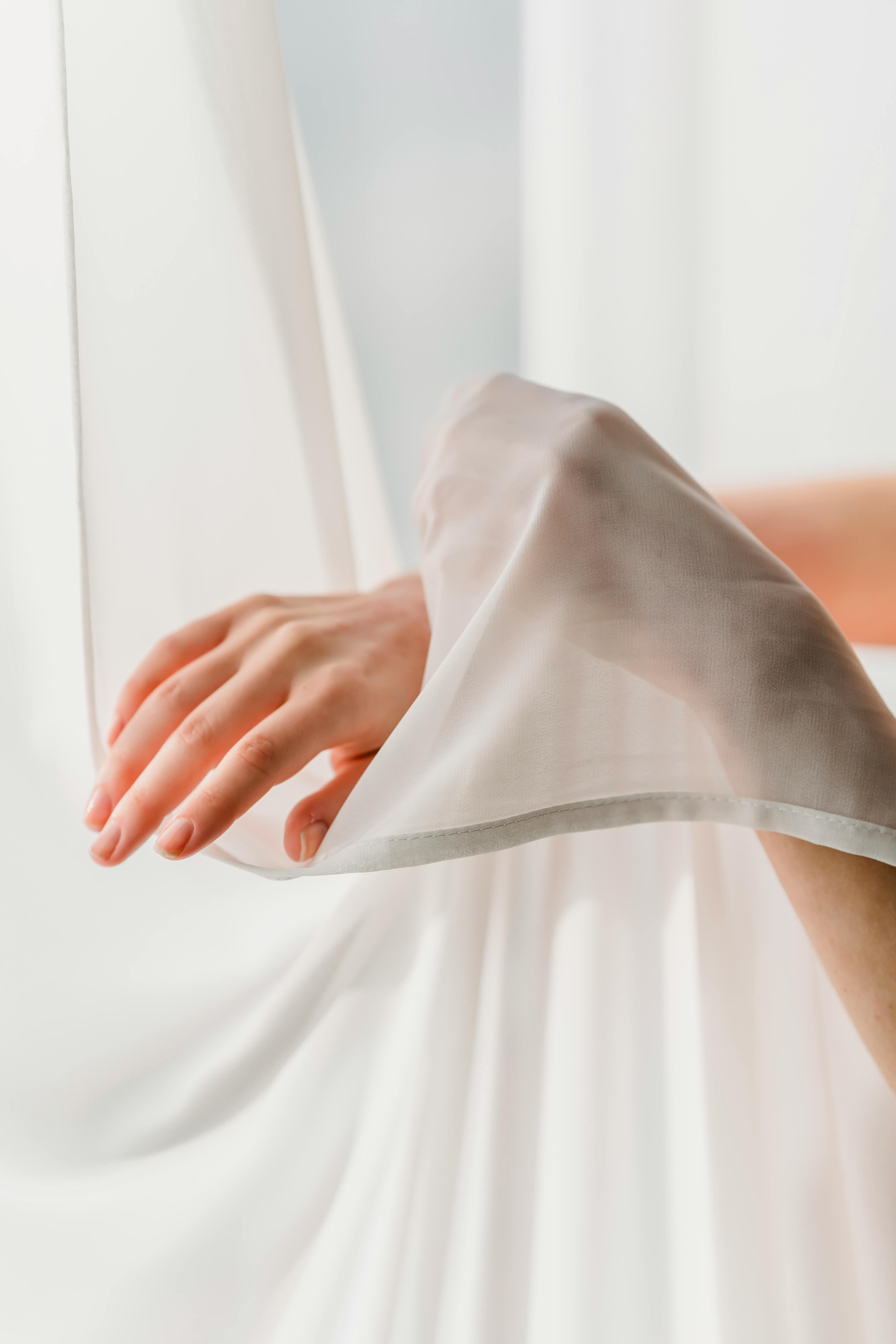 faceless woman touching chiffon curtains tenderly
