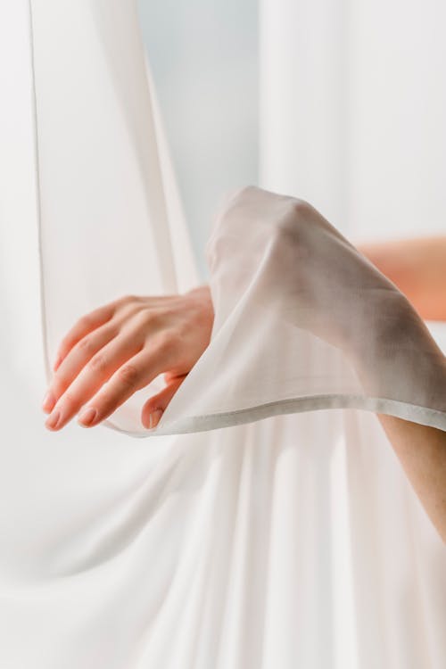 Faceless woman touching chiffon curtains tenderly