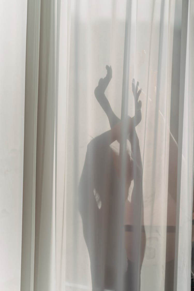 Silhouette Of Unrecognizable Woman Dancing Behind Chiffon Curtains