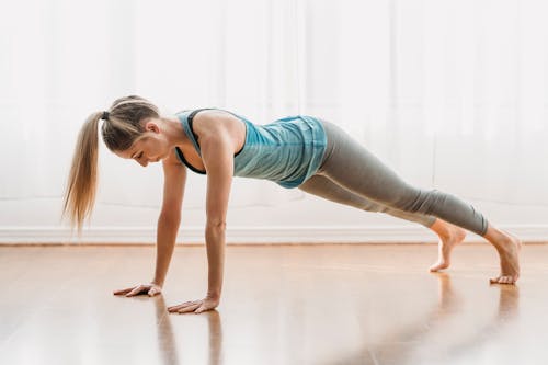 Wanita Dengan Tank Top Biru Dan Legging Abu Abu Melakukan Yoga