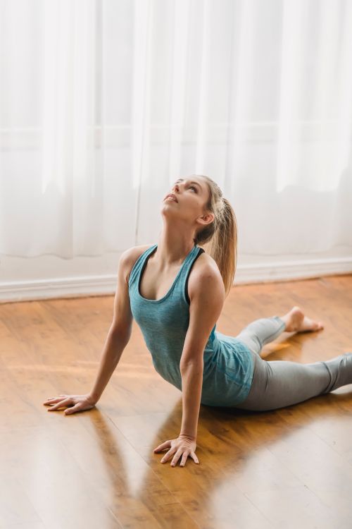 Free Flexible female in activewear performing Urdhva Mukha Svanasana on timber clean floor at home Stock Photo