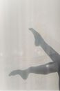 Shadow of feminine legs on white wall