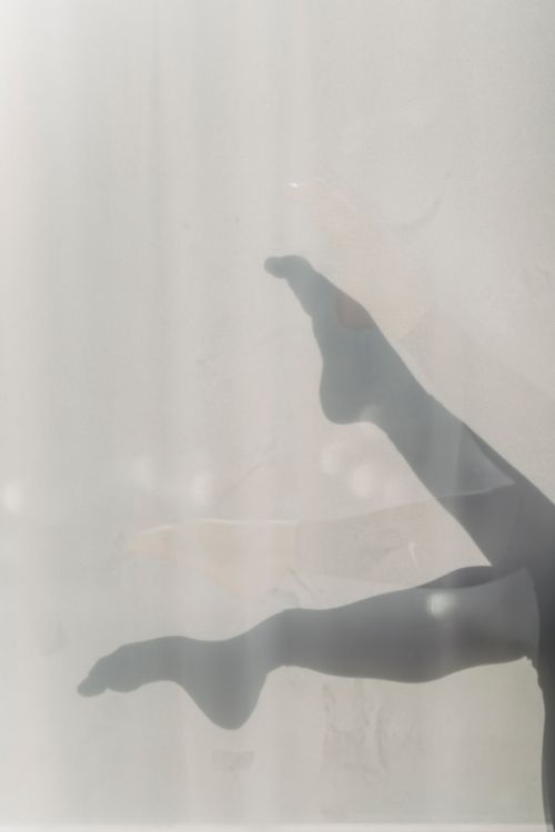 Free Crop anonymous female demonstrating slender legs on white wall in apartment in daylight Stock Photo