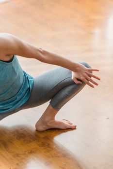 From above of crop anonymous female doing stretching on timber floor at home