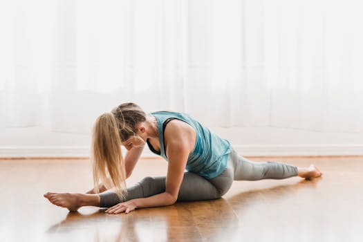 Full body of slender female doing splits on timber clean floor at home with transparent curtains