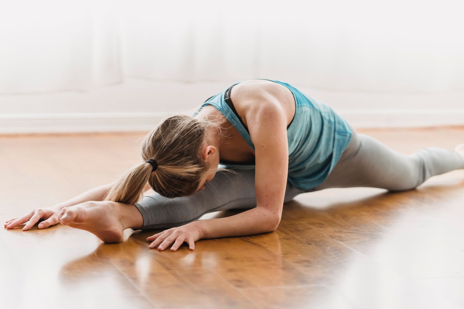 Woman practicing a seated yoga leg stretch on a mat to help tone and reduce thigh fat