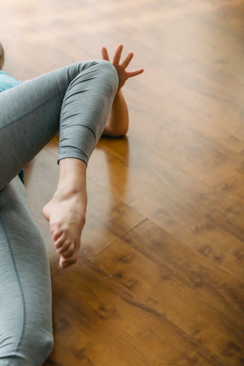 Barefoot woman lying on wooden floor and doing exercises