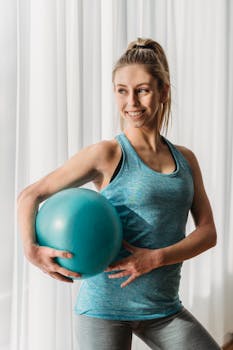 Cheerful woman holding an exercise ball, promoting fitness and wellness.