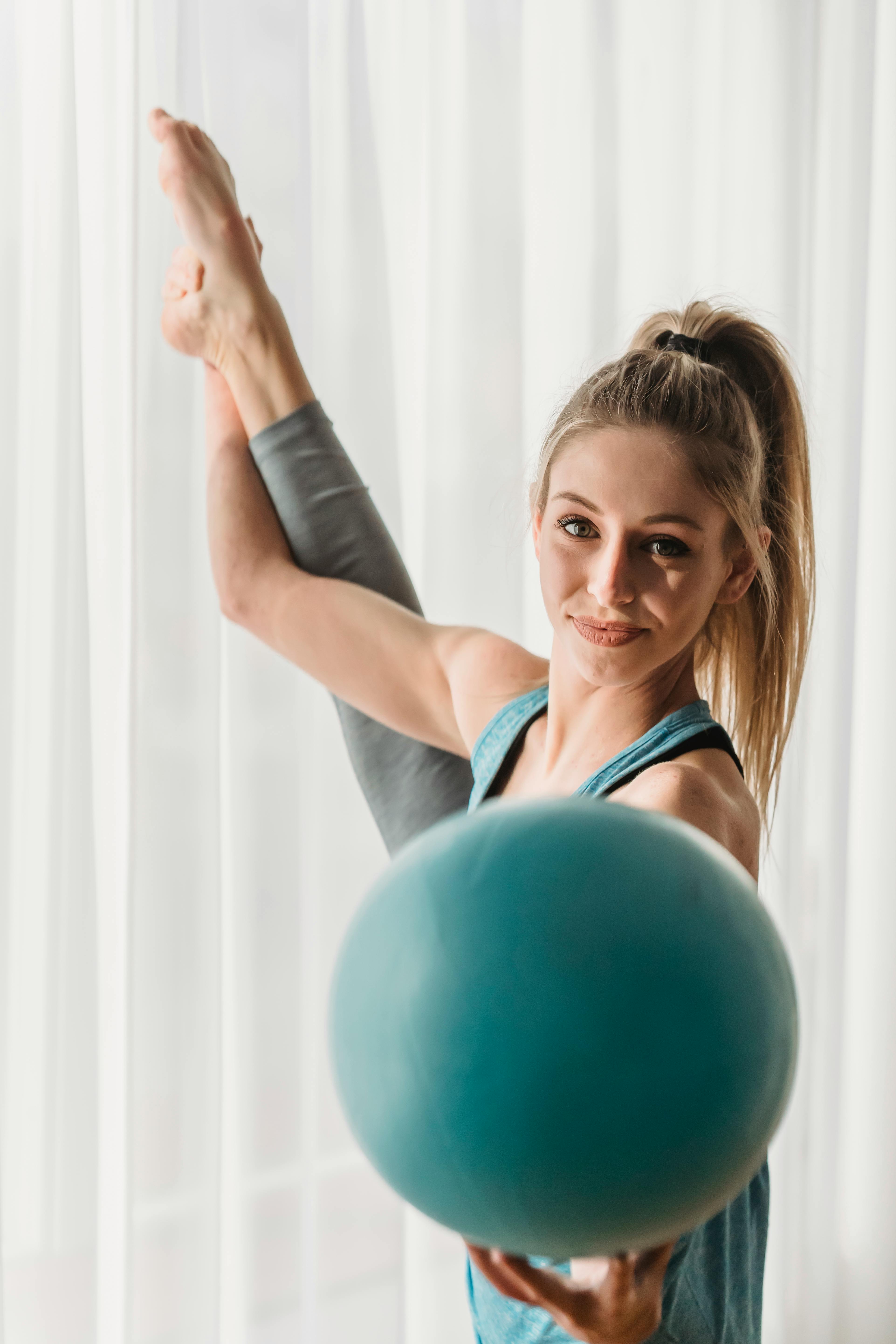 Charming woman with fit ball stretching leg · Free Stock Photo