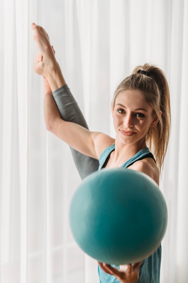 Charming Woman With Fit Ball Stretching Leg