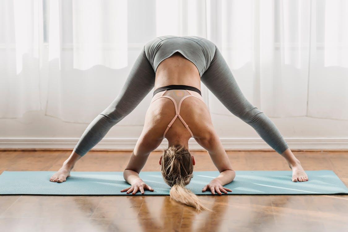 Slim woman doing yoga in Wide Legged Forward Bend pose · Free Stock Photo