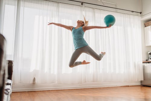 Free Slim woman in sportswear jumping up with ball Stock Photo