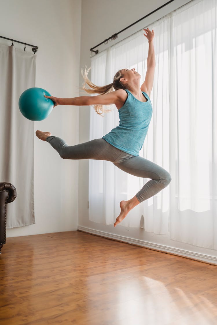 Sporty Young Woman Jumping With Medicine Ball During Workout