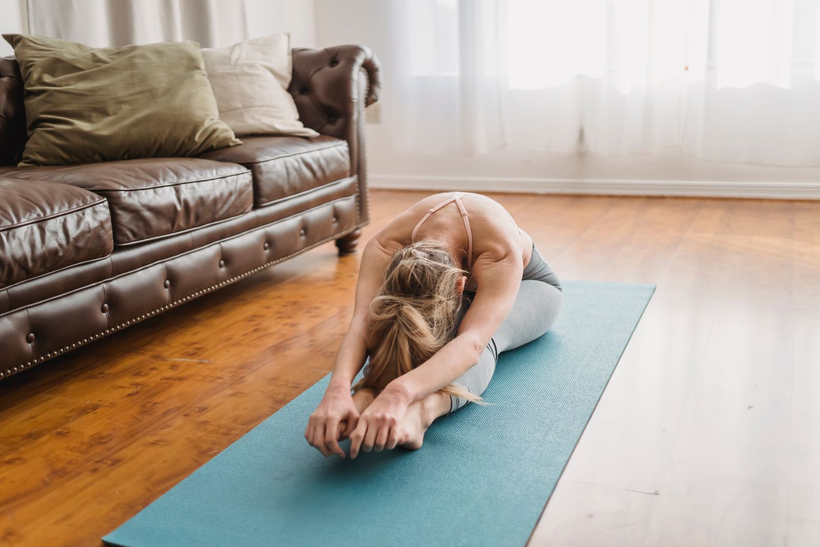 Woman performing Paschimottanasana seated forward bend yoga pose at home for diabetes management