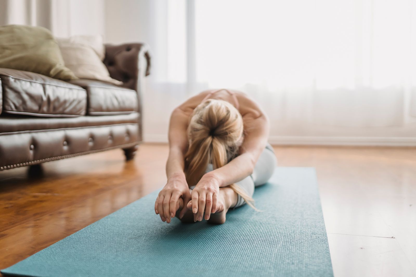 Woman performing Paschimottanasana seated forward bend yoga pose for improved circulation and hair health