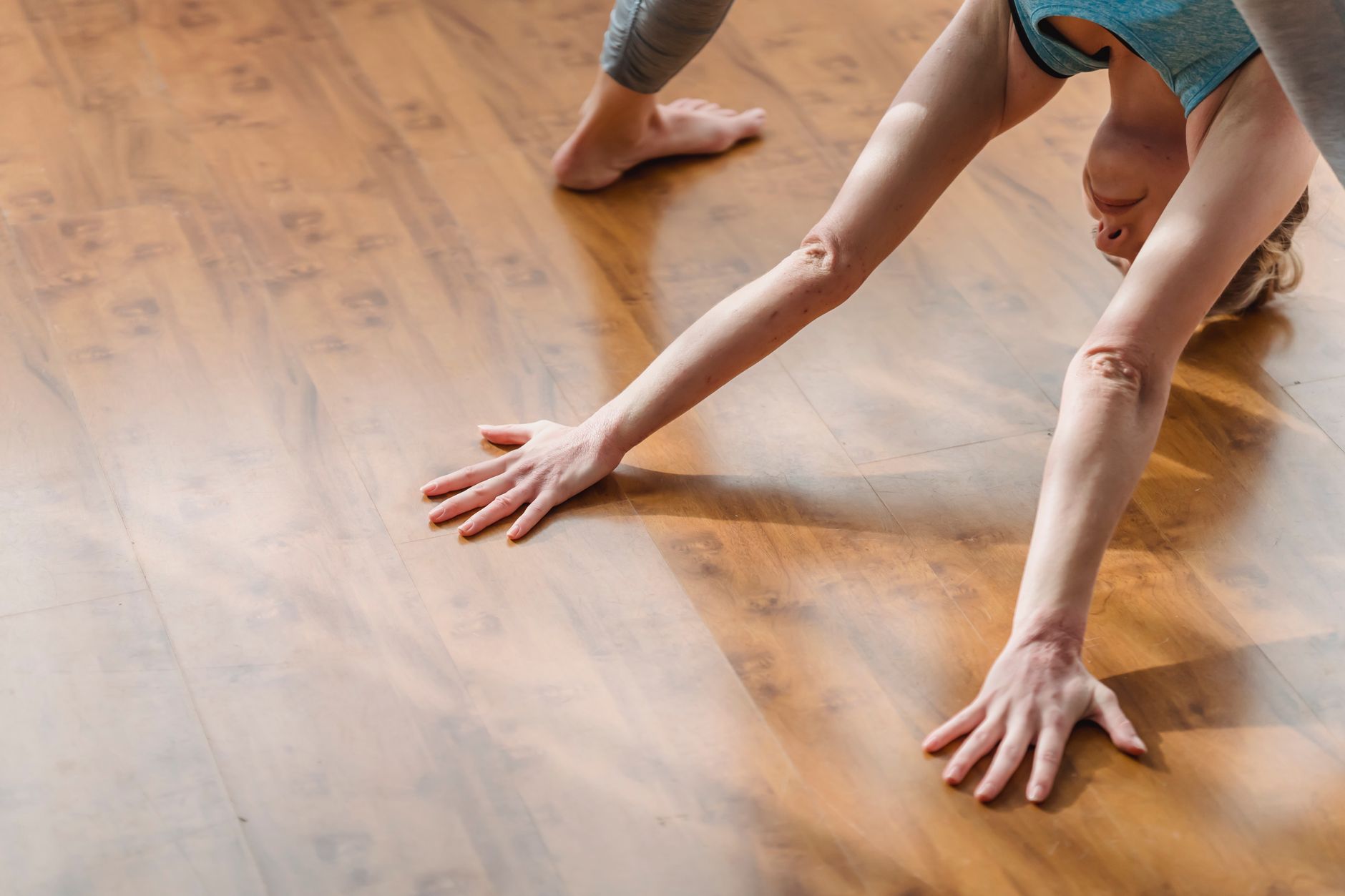 From above of concentrated young barefooted lady in activewear lengthening body while performing Wide Legged Forward Bend I asana during yoga session at home