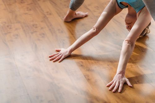 Free From above of concentrated young barefooted lady in activewear lengthening body while performing Wide Legged Forward Bend I asana during yoga session at home Stock Photo