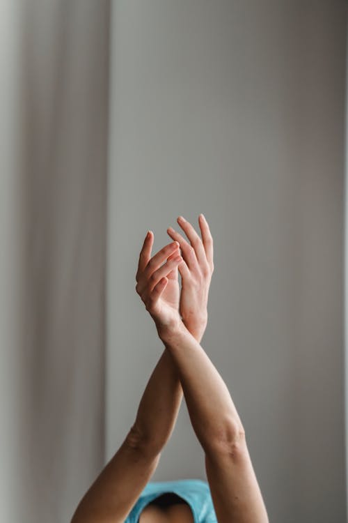 Anonymous woman performing dance with raised arms in studio