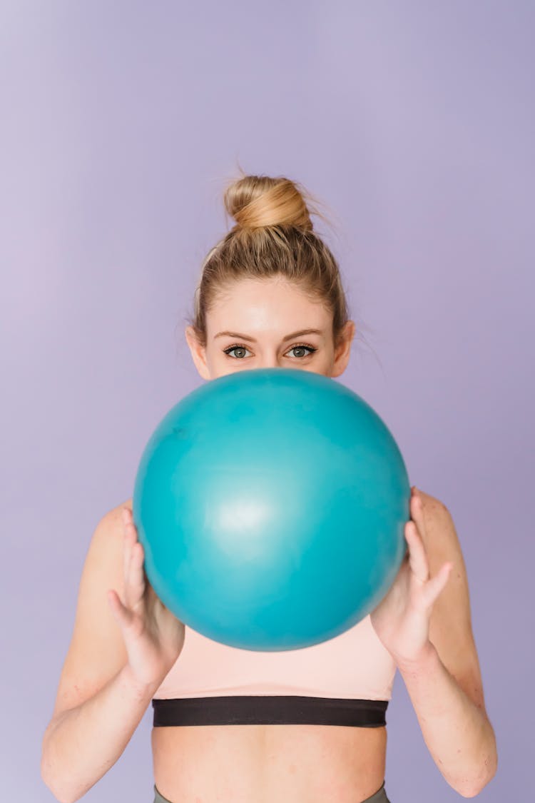 Young Woman Covering Face With Fitness Ball