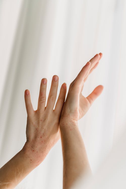 Low angle of crop faceless female gently touching raised hands near thin curtain