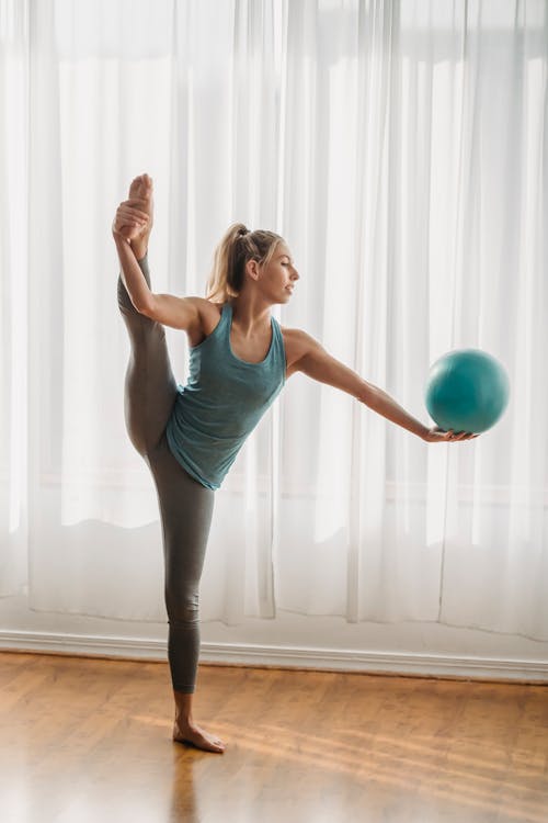 Wanita Dengan Tank Top Biru Dan Legging Hitam Memegang Bola Biru