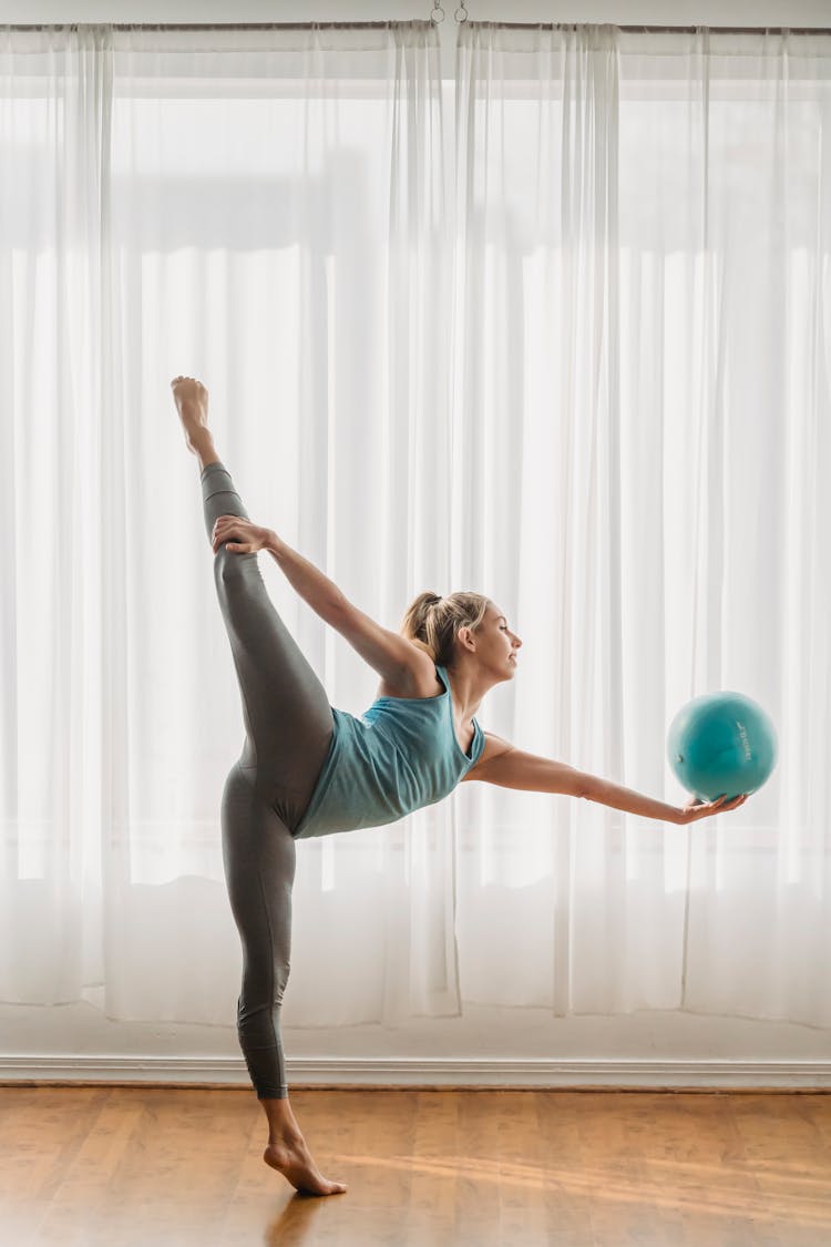 Graceful Female Practicing Yoga With Ball And Doing Natarajasana Pose