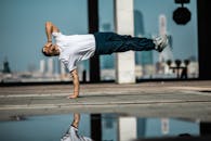 A Man in White Shirt Doing Handstand while Covering His Face