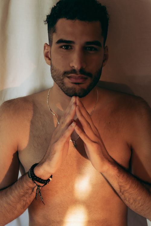 Free Portrait of a shirtless man with hands clasped, evoking deep thought and calm. Stock Photo