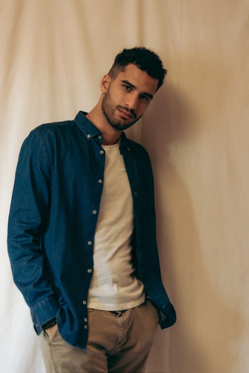 Free Stylish portrait of a young man in a denim shirt posing confidently indoors. Stock Photo