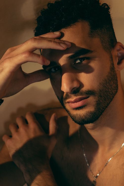 Free A moody close-up portrait of a serious man with curly hair, deep in thought. Stock Photo
