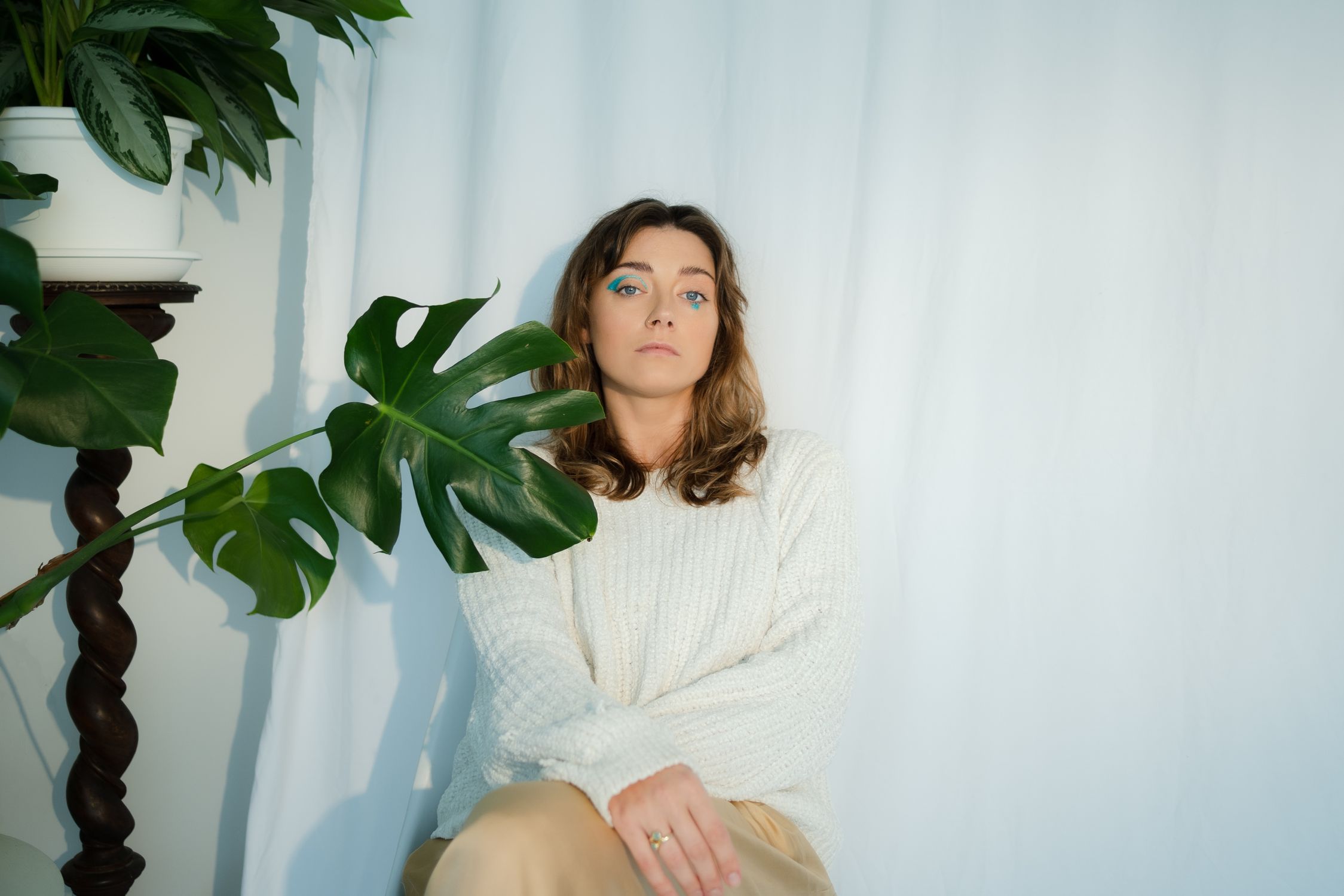 A Woman in White Knit Sweater Sitting Beside Green Plant · Free Stock Photo