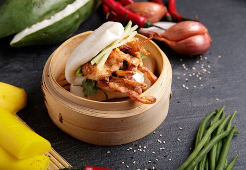 Delicious steamed bao with soft shell crab, garnished with vegetables, in a bamboo steamer.