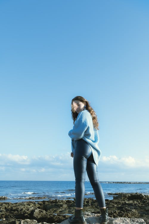 蓝色长袖衬衫和黑色的裤子，站在海边的女人