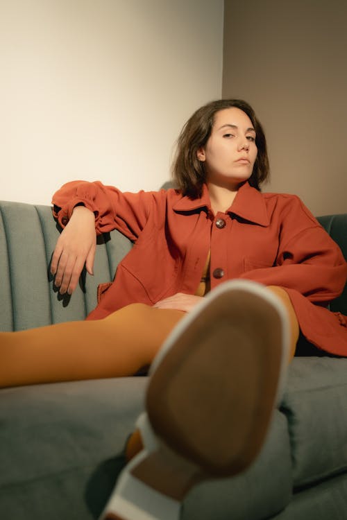 灰色のソファに座っている赤いドレスシャツの女性