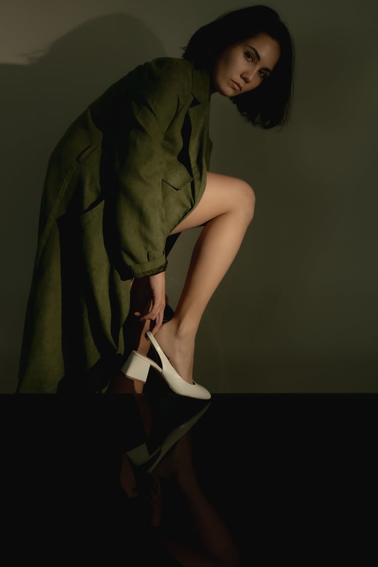 Woman In Green Coat Putting On White Shoe