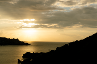 A Sun Setting Over Silhouette Mountains Surrounded by the Sea