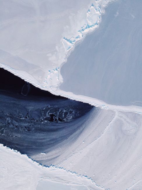 A stunning aerial view of ice cracks and snow on a frozen surface in winter.
